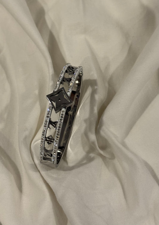 Silver-toned cuff with a cutout pattern and rhinestone